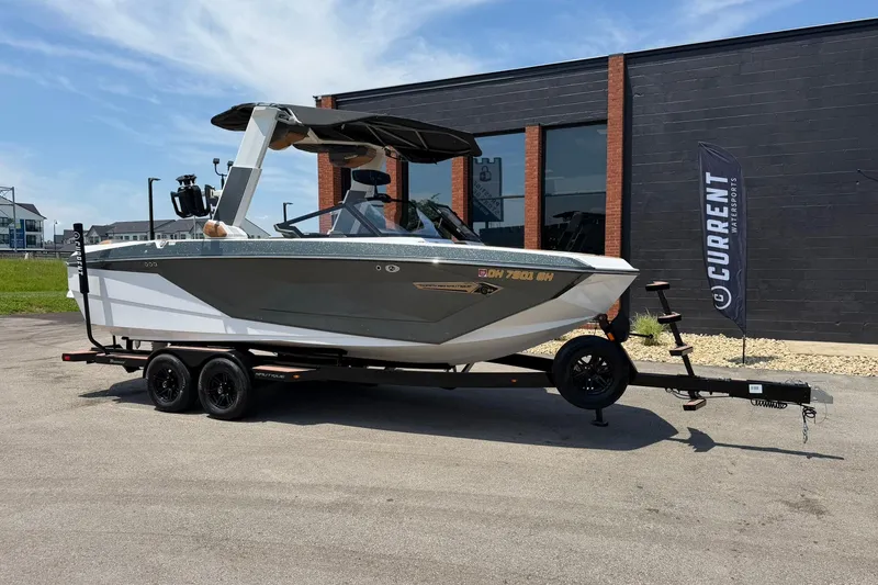 The Image of 2022 Nautique Super Air Nautique G23 boat on trailer, parked outside a building. - 1