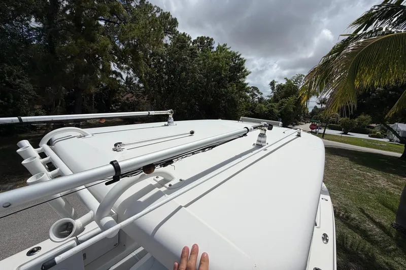 Slide: The Image of 2019 Robalo R272 Center Console boat with fishing rod holders, parked near trees and road. - 15