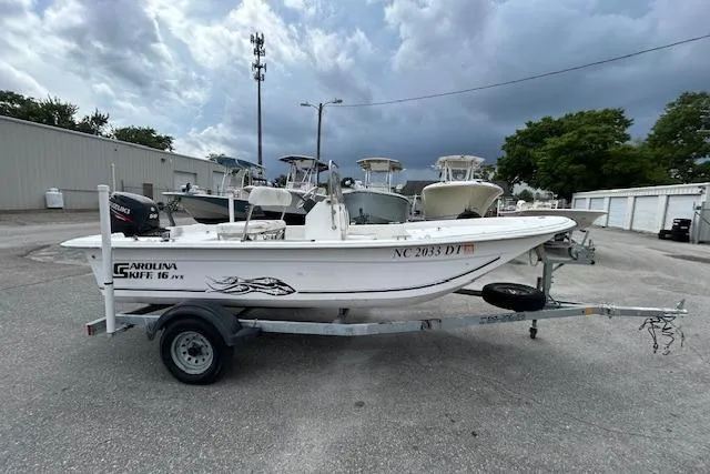 The Image of 2011 Carolina Skiff JVX16CC boat on trailer, parked outdoors under cloudy sky. - 1
