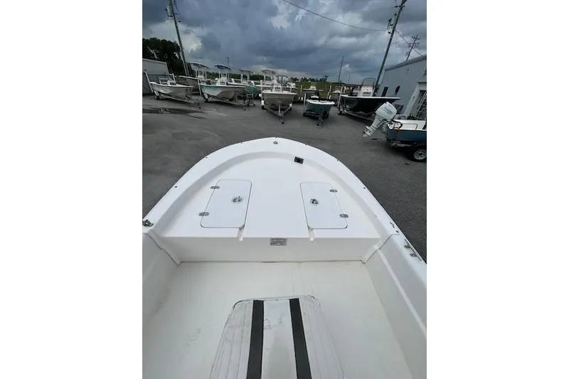 Slide: The Image of 2011 Carolina Skiff JVX16CC boat deck view, parked with other boats under cloudy sky. - 5