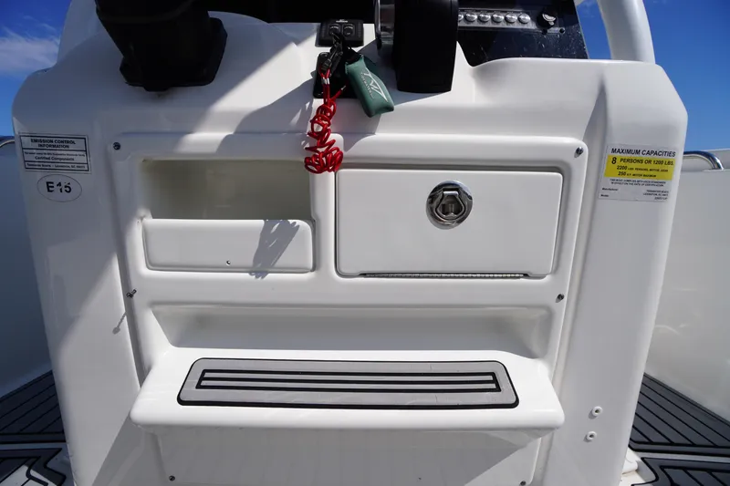 Slide: The Image of 2020 Tidewater 220 LXF boat console with storage compartments and safety labels. - 16