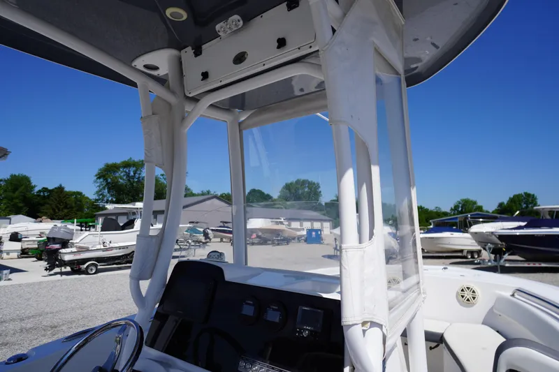 Slide: The Image of 2020 Tidewater 220 LXF boat interior with console and canopy, parked in a marina. - 28