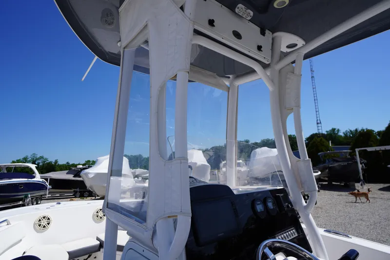 Slide: The Image of 2020 Tidewater 220 LXF boat interior with console and clear enclosure, parked outdoors. - 29