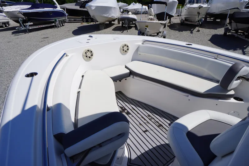 Slide: The Image of 2020 Tidewater 220 LXF boat interior with white seating and deck, parked among other boats. - 4