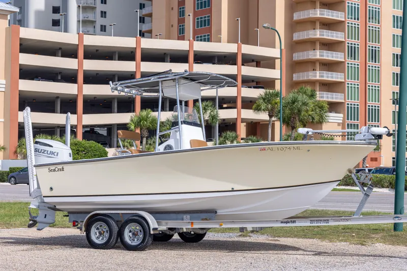 The Image of 2004 Sea Craft 23 CC boat on trailer, parked near modern buildings. - 0
