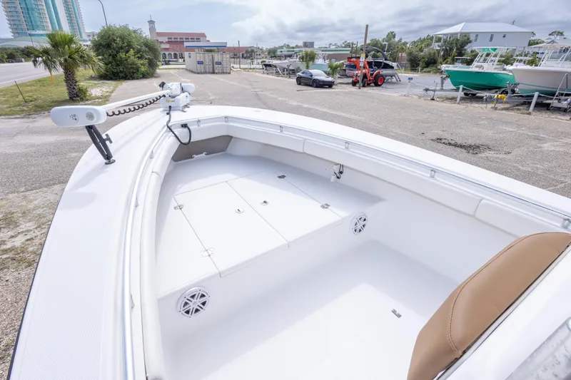 Slide: The Image of 2004 Sea Craft 23 CC boat deck with storage compartments and seating, parked near marina. - 26
