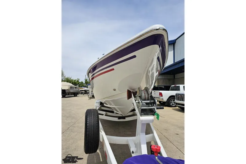 Slide: The Image of 2005 Baja 30 Outlaw boat on trailer, parked outdoors near other vehicles. - 16