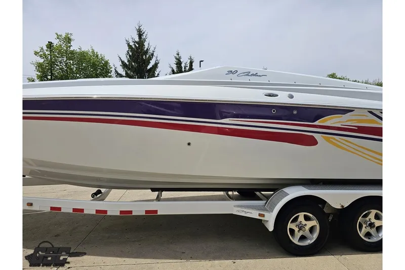 Slide: The Image of 2005 Baja 30 Outlaw boat on trailer with colorful graphics, parked outdoors. - 22