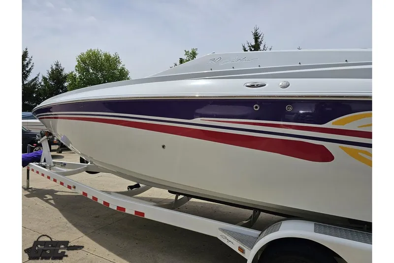 Slide: The Image of 2005 Baja 30 Outlaw boat on trailer with colorful graphics, parked outdoors. - 24