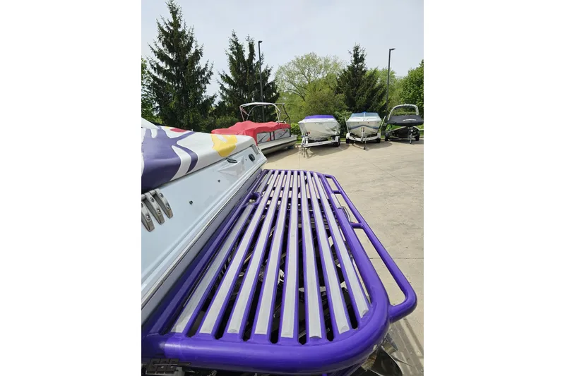 Slide: The Image of 2005 Baja 30 Outlaw boat with vibrant purple detailing, parked among other boats. - 28