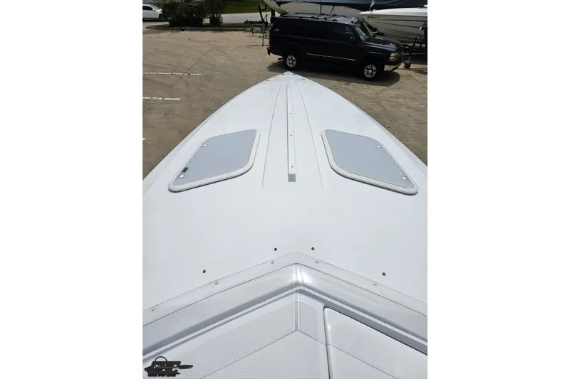 Slide: The Image of 2005 Baja 30 Outlaw boat deck view with hatches, parked in a marina. - 62