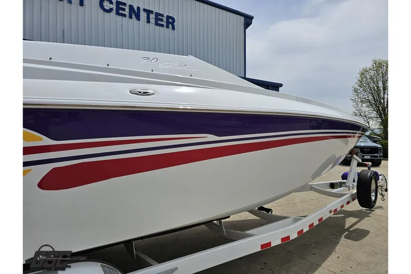 Slide: The Image of 2005 Baja 30 Outlaw boat with colorful stripes on trailer, parked outside a service center. - 8
