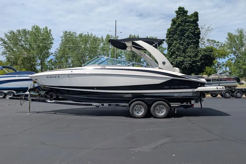 Slide: The Image of 2017 Regal 2500 Bowrider boat on trailer, parked outdoors with trees in background. - 1