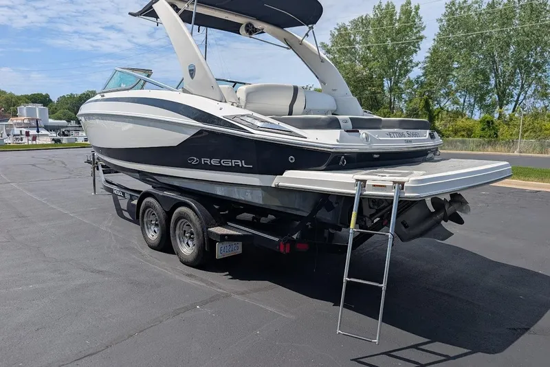 Slide: The Image of 2017 Regal 2500 Bowrider boat on trailer, parked outdoors with trees in background. - 8