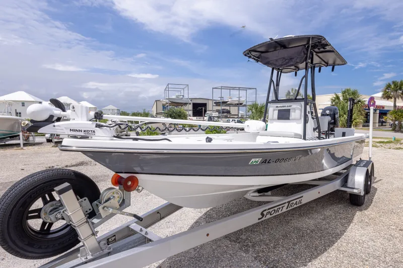 Slide: The Image of 2023 Blazer Bay 2200 boat on trailer with Minn Kota motor, parked outdoors. - 11