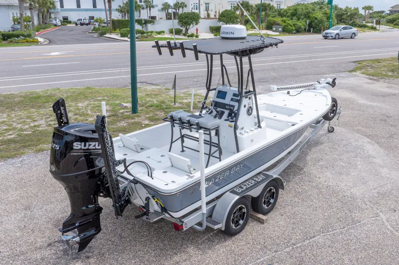 Slide: The Image of 2023 Blazer Bay 2200 boat with Suzuki engine on a trailer, parked near a road. - 14