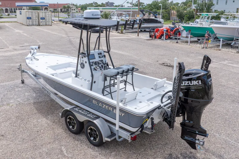 Slide: The Image of 2023 Blazer Bay 2200 boat on trailer with Suzuki outboard motor in a marina setting. - 15