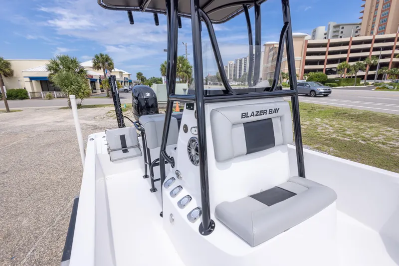 Slide: The Image of 2023 Blazer Bay 2200 boat interior with seating and controls, parked near a road. - 38