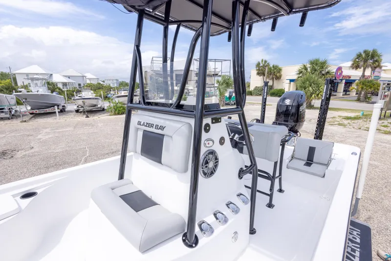 Slide: The Image of 2023 Blazer Bay 2200 boat with T-top and Suzuki outboard motor in a marina setting. - 40