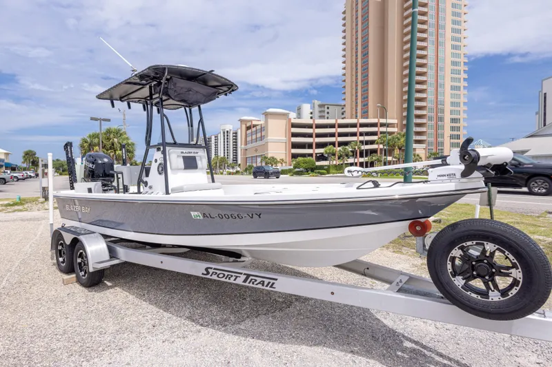 Slide: The Image of 2023 Blazer Bay 2200 boat on trailer, parked near tall buildings. - 5