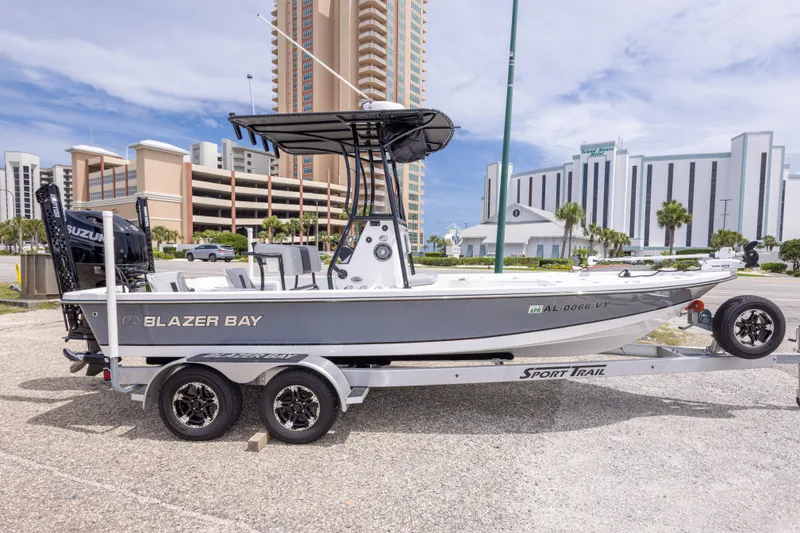 Slide: The Image of 2023 Blazer Bay 2200 boat on trailer, parked near modern buildings. - 6