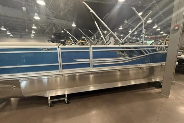 Slide: The Image of 2026 SunCatcher Select 322SL pontoon boat displayed indoors, featuring a sleek blue design. - 5