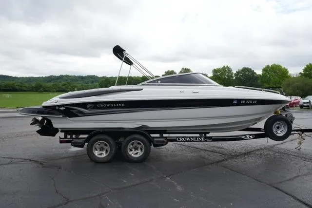 Slide: The Image of 2008 Crownline 230 LS boat on trailer, parked outdoors with green landscape background. - 4