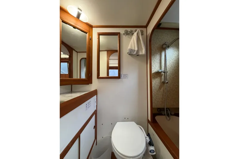 Slide: The Image of Compact bathroom in a 1988 Monk 36 boat, featuring a shower, toilet, and wooden accents. - 21