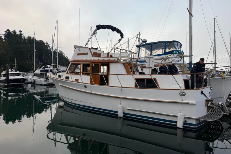 Slide: The Image of 1988 Monk 36 yacht docked in a marina, surrounded by other boats and calm water. - 3