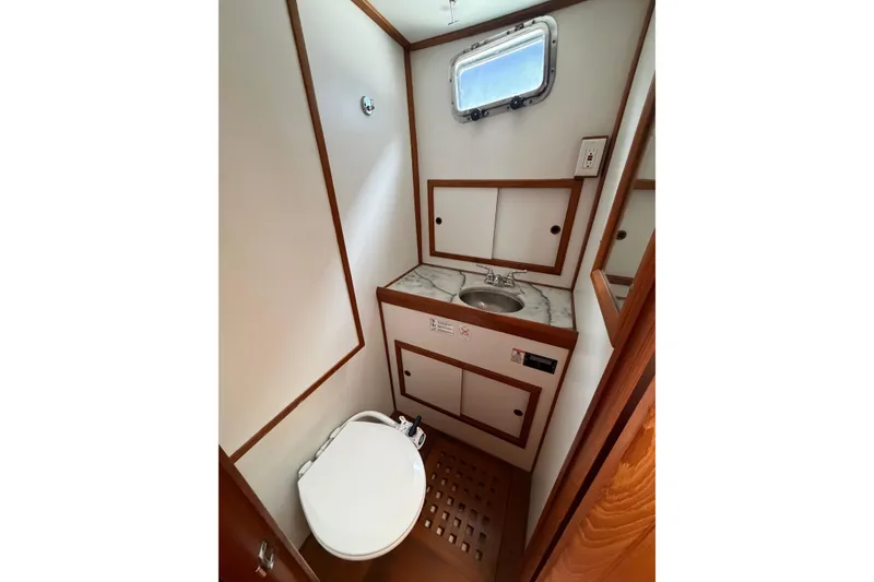 Slide: The Image of Compact bathroom in a 1988 Monk 36 boat, featuring a sink, toilet, and wooden accents. - 15