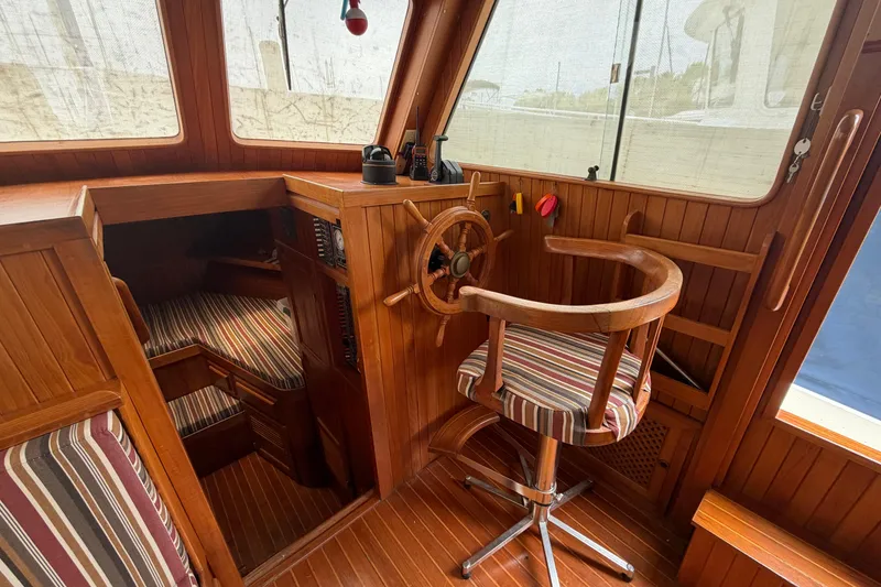 Slide: The Image of 1988 Monk 36 boat interior with wooden helm, striped seating, and nautical decor. - 5