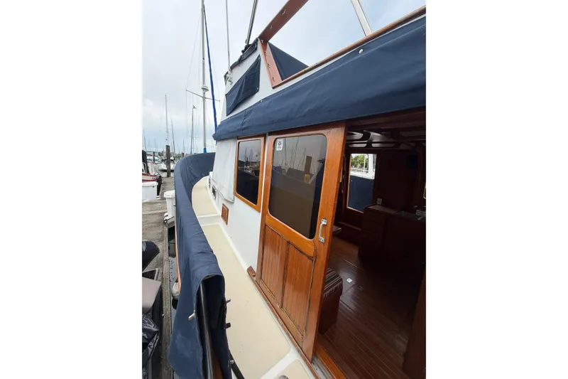 Slide: The Image of 1988 Monk 36 boat with wooden cabin and blue canopy docked at marina. - 23