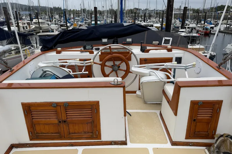Slide: The Image of 1988 Monk 36 yacht helm with wooden accents, docked in a marina. - 27