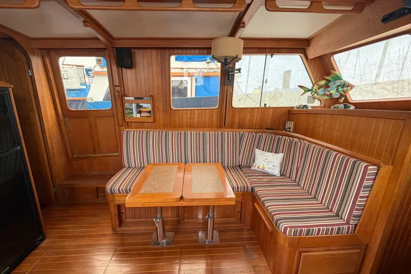 Slide: The Image of 1988 Monk 36 yacht interior with striped seating, wooden table, and nautical decor. - 8
