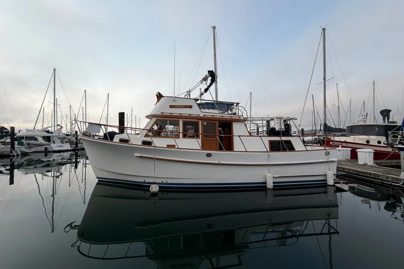 Slide: The Image of 1988 Monk 36 boat docked in a marina, surrounded by sailboats. - 2