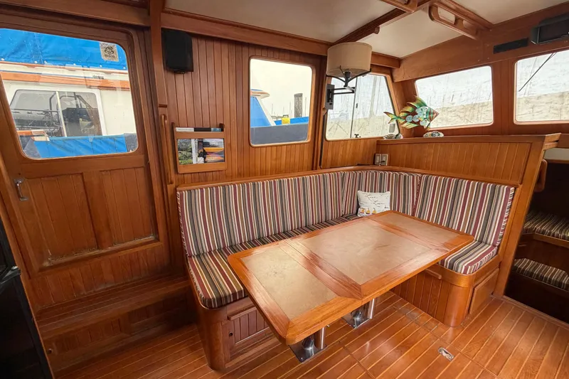 Slide: The Image of Cozy 1988 Monk 36 boat interior with striped seating and wooden table. - 7