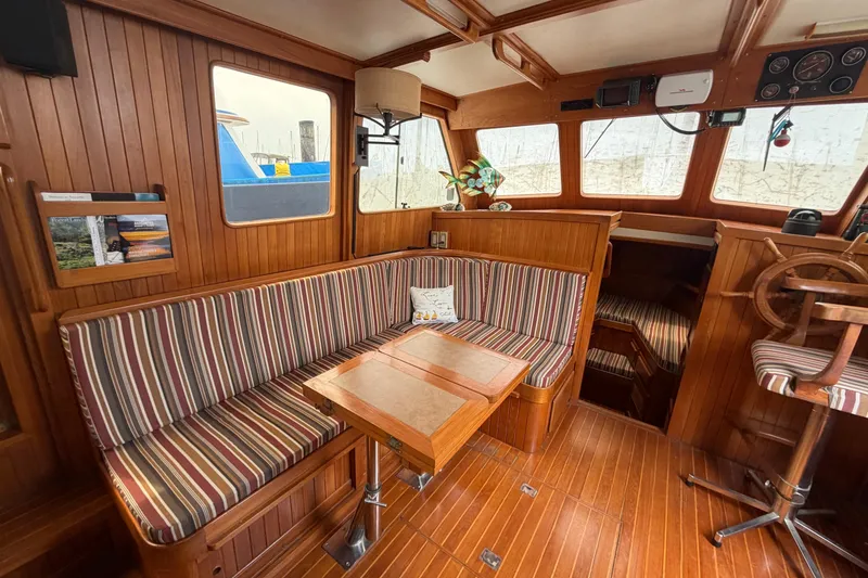 Slide: The Image of Cozy 1988 Monk 36 boat interior with striped seating, wooden accents, and helm station. - 4