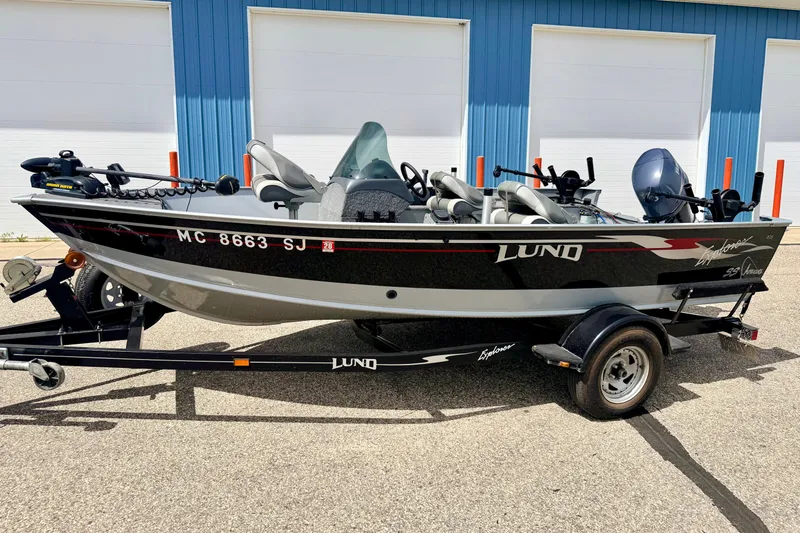 Slide: The Image of 2003 Lund 1675 Adventure SS boat on trailer, parked outside blue building. - 1