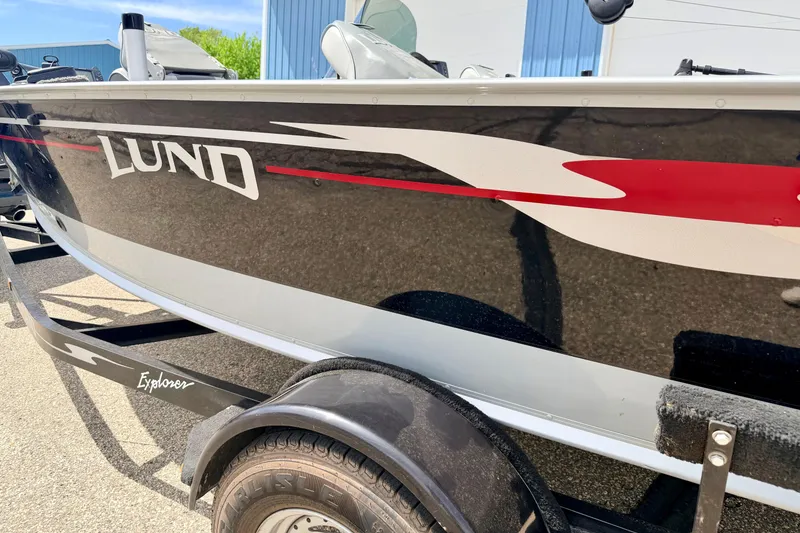 Slide: The Image of 2003 Lund 1675 Adventure SS boat on trailer, featuring sleek black and red design. - 11