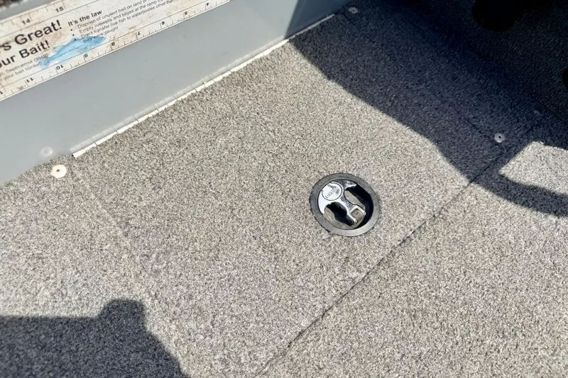 Slide: The Image of Carpeted floor of a 2003 Lund 1675 Adventure SS boat with a metal latch. - 67