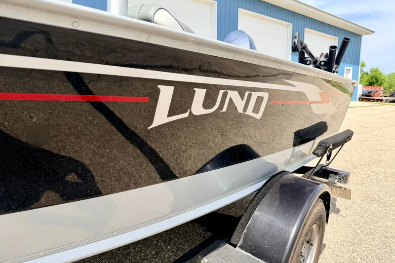 Slide: The Image of 2003 Lund 1675 Adventure SS boat on trailer, parked near blue building. - 7
