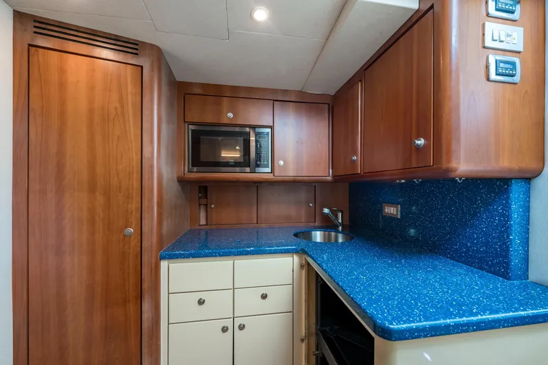 Slide: The Image of 2008 Ocean Yacht 37 Billfish galley with blue countertop, wooden cabinets, and microwave. - 19