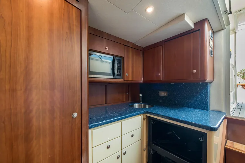 Slide: The Image of Compact yacht kitchen with wooden cabinets, blue countertop, and built-in microwave on Ocean Yacht 37 Billfish. - 20