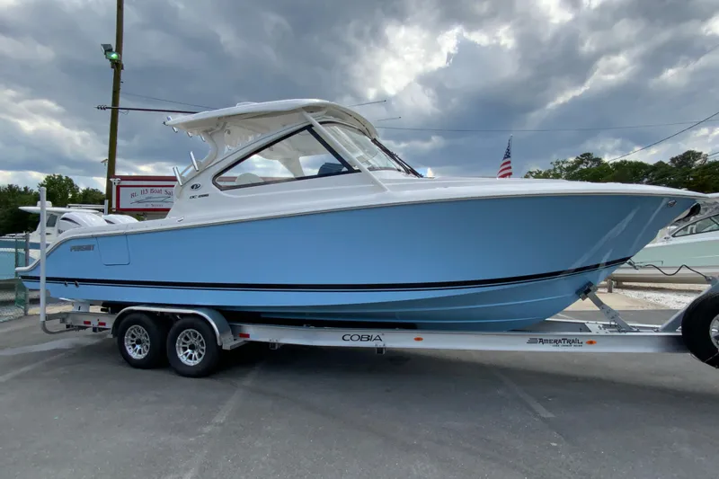 Slide: The Image of 2026 Pursuit DC 286 Dual Console boat on trailer, under cloudy sky. - 2