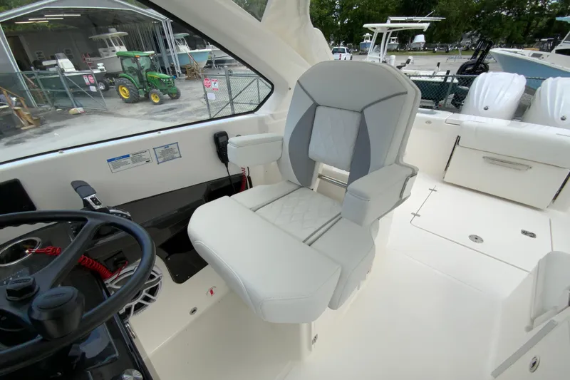 Slide: The Image of 2026 Pursuit DC 286 Dual Console boat interior with steering wheel and cushioned seating. - 26