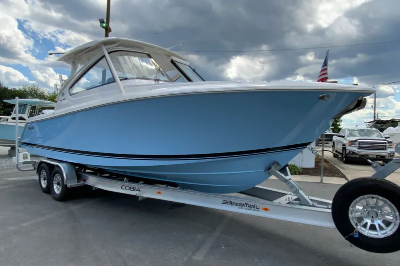 Slide: The Image of 2026 Pursuit DC 286 Dual Console boat on trailer under cloudy sky. - 3