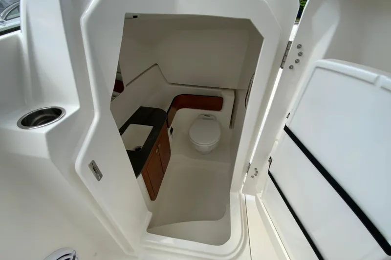 Slide: The Image of Interior of 2026 Pursuit DC 286 Dual Console boat, featuring a compact marine toilet. - 35