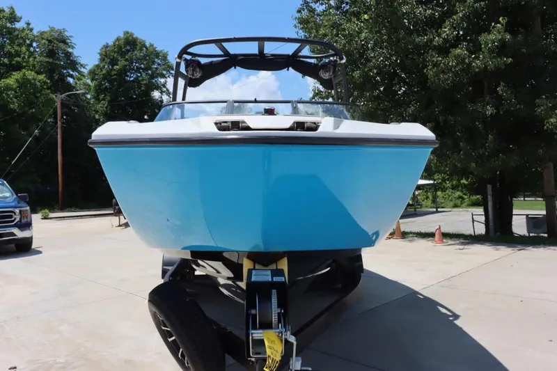 Slide: The Image of 2023 Yamaha Boats AR250 in blue on trailer, parked outdoors. - 2