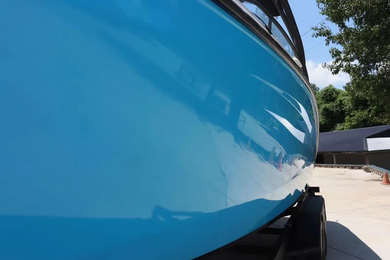 Slide: The Image of 2023 Yamaha Boats AR250 in vibrant blue, parked outdoors on a sunny day. - 34