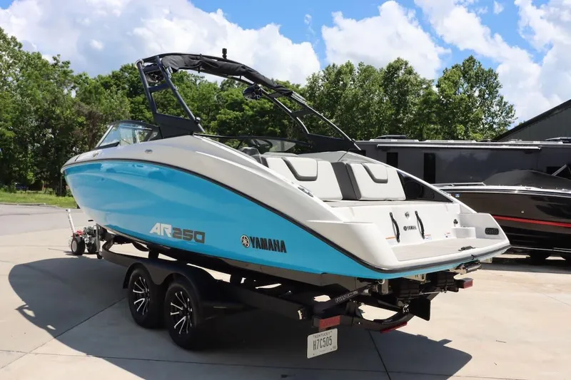 Slide: The Image of 2023 Yamaha Boats AR250 in blue, parked on a trailer under a clear sky. - 4
